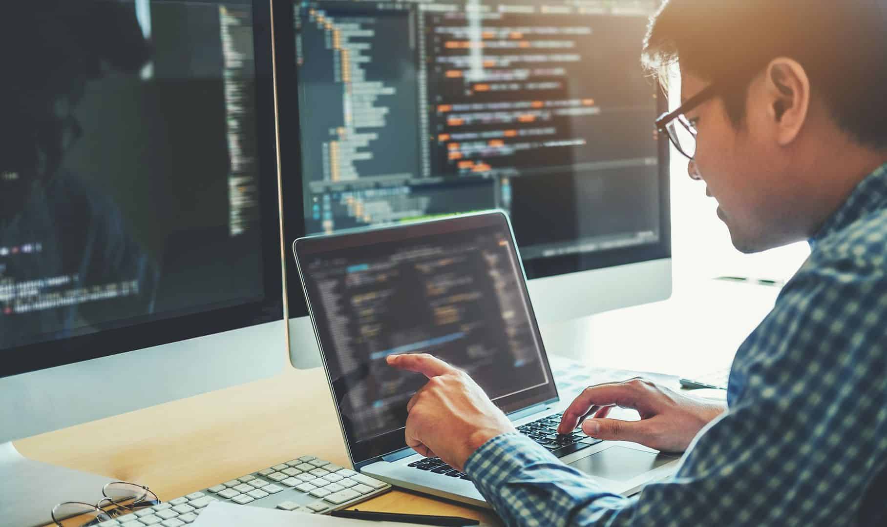 A man working on a laptop, pointing at the screen.